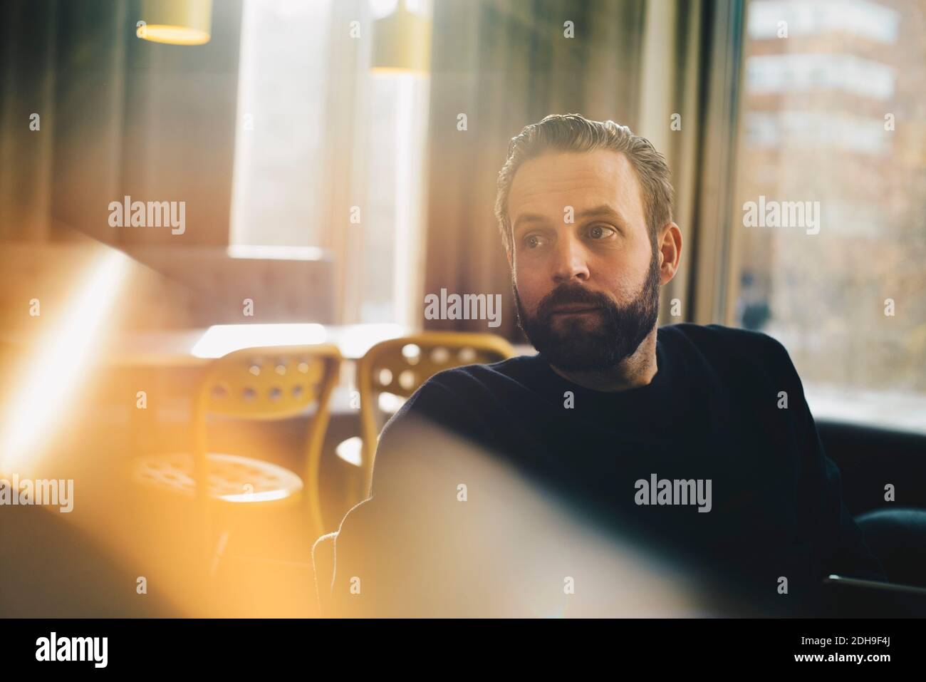 Ein nachdenklicher Geschäftsmann, der in einem hell erleuchteten Büro sitzt Stockfoto