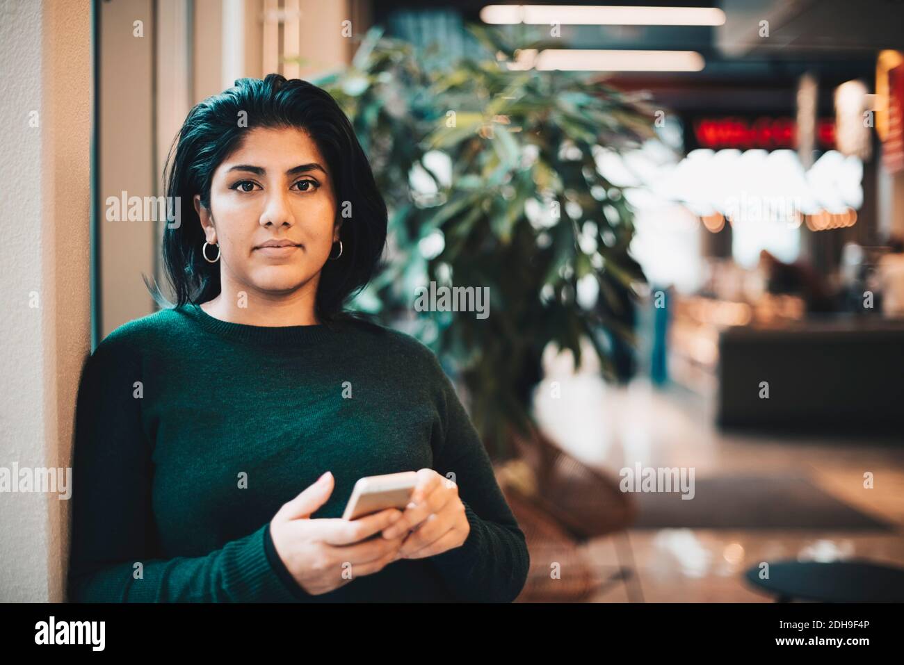 Porträt einer selbstbewussten Geschäftsfrau mit Smartphone im Büro Stockfoto