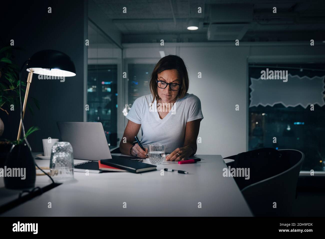 Frau, die spät am Schreibtisch im Büro arbeitet Stockfoto