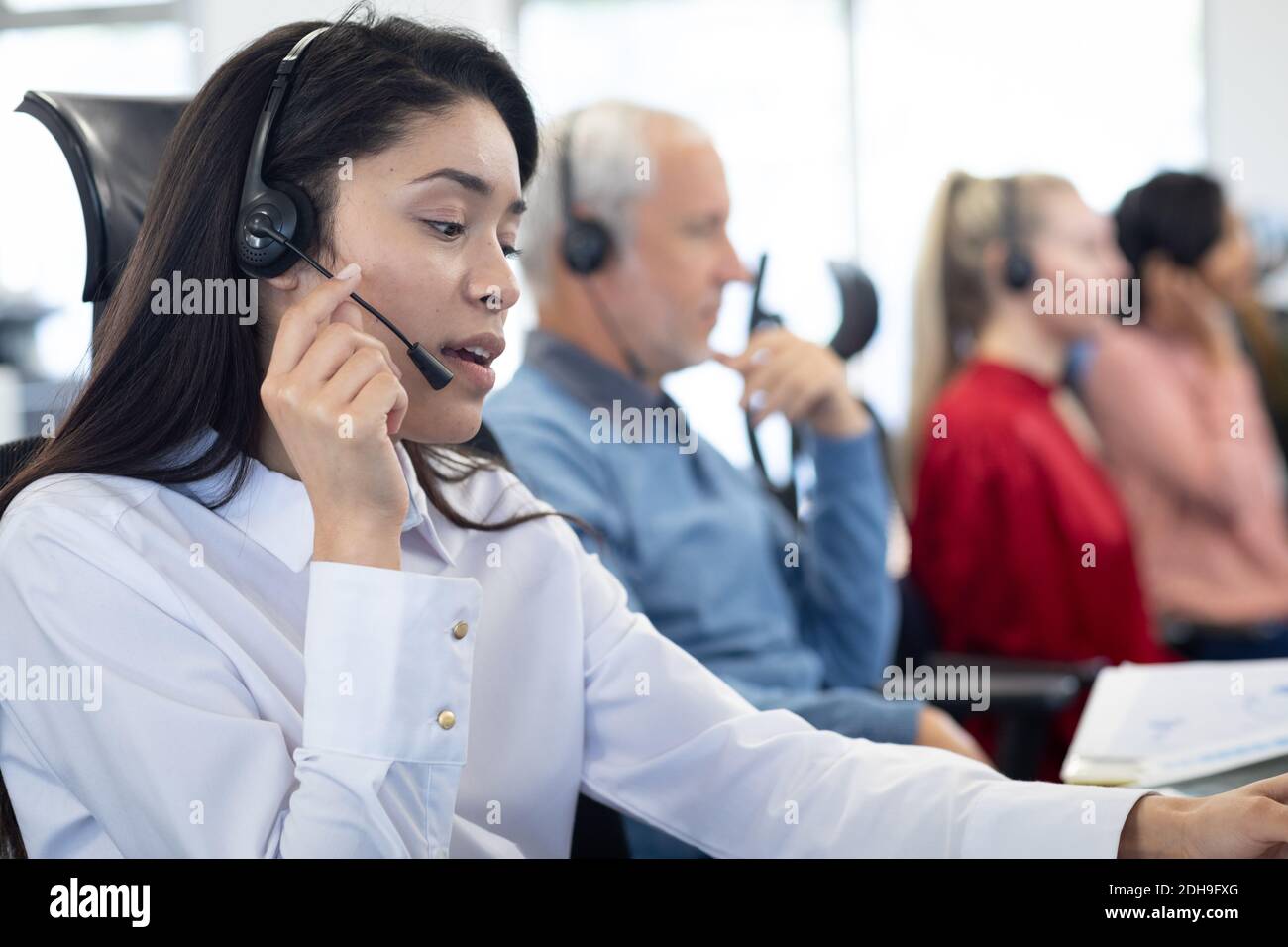 Geschäftsfrau mit Headset bei der Arbeit im Büro Stockfoto