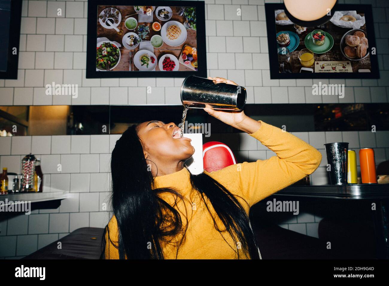 Frau, die Wasser aus Glas im Café trinkt Stockfoto