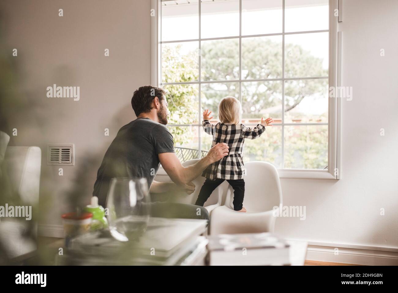 Mitte erwachsener Mann mit Tochter Blick durch Fenster zu Hause Stockfoto Mitte erwachsener Mann mit Tochter Blick durch Fenster zu Hause Stockfoto