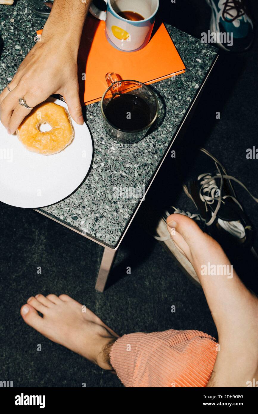 High-Angle-Ansicht des Mannes essen Donut in kreativen Büro Stockfoto