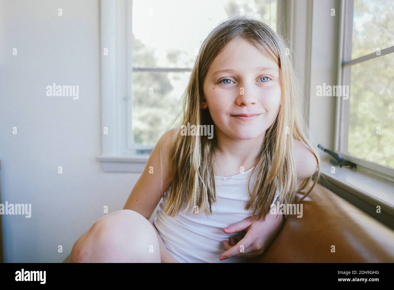 Nachdenkliches Mädchen, das zu Hause auf dem Sofa am Fenster sitzt Stockfoto