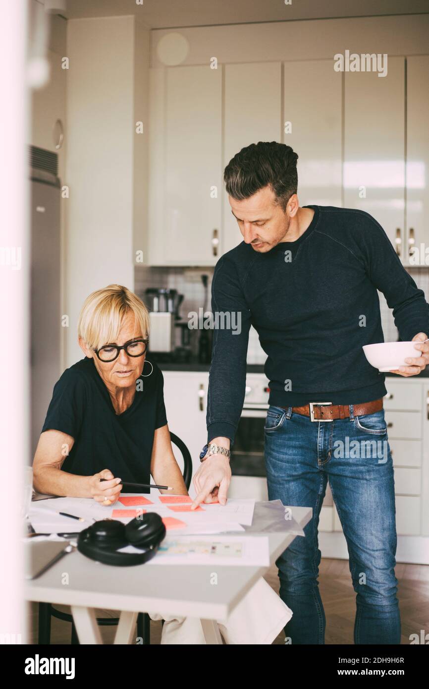 Mann und Frau diskutieren über Blaupause, die zu Hause arbeitet Stockfoto