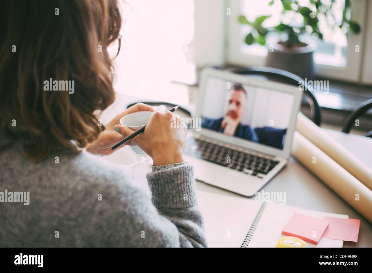 Frau im Heimbüro mit Online-Meeting mit Kollegen Stockfoto
