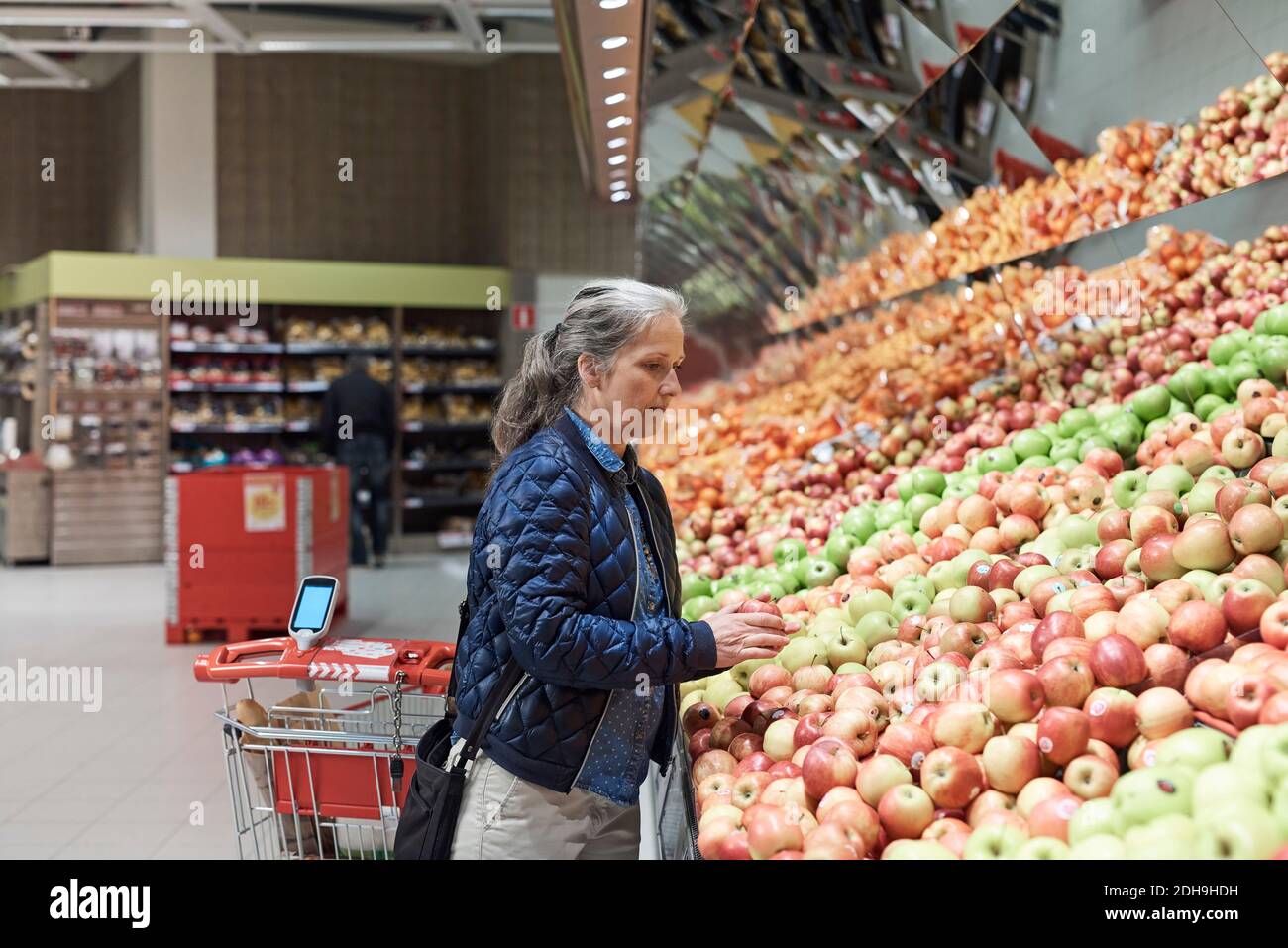 Reife Frau beim Kauf von Äpfeln im Supermarkt Stockfoto