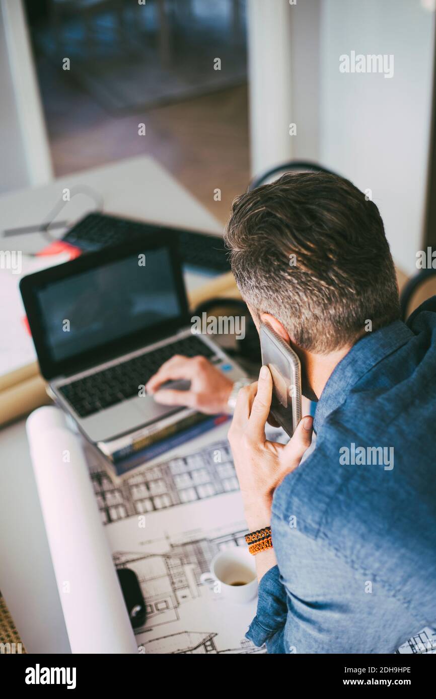 Beschäftigt Mann am Telefon mit Laptop zu Hause Stockfoto