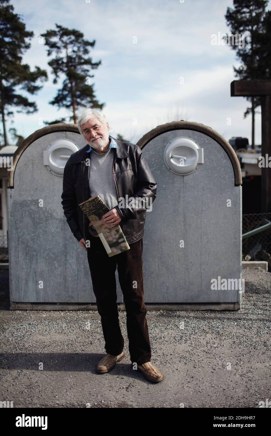 Porträt eines älteren Mannes, der gegen Mülltonnen in der Stadt steht Stockfoto