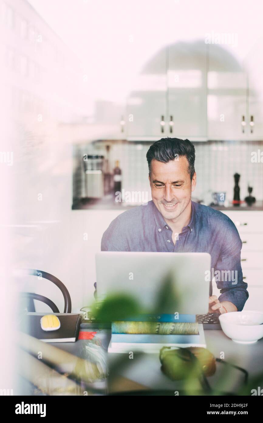 Glücklicher Mann, der Videoanruf in der Küche hat, der zu Hause arbeitet Stockfoto