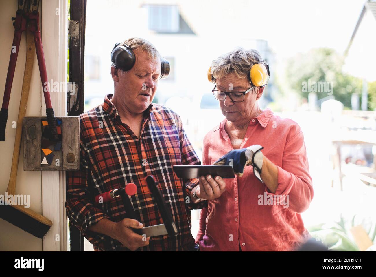 Seniorenpaar diskutiert über digitale Tablet während der Werkstatt stehen Eingang Stockfoto