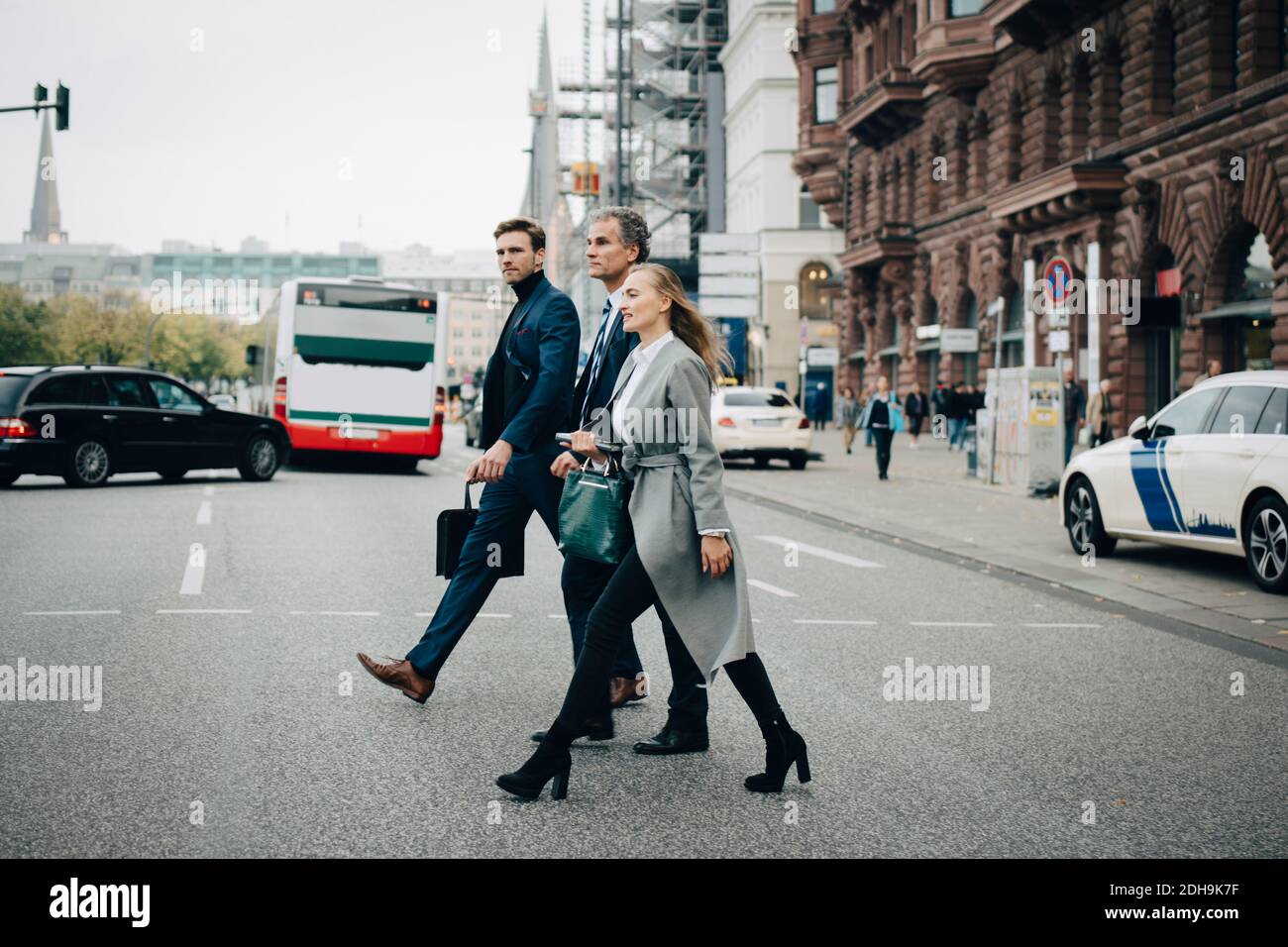 Geschäftsfrau mit männlichen Kollegen überqueren Straße in der Stadt Stockfoto
