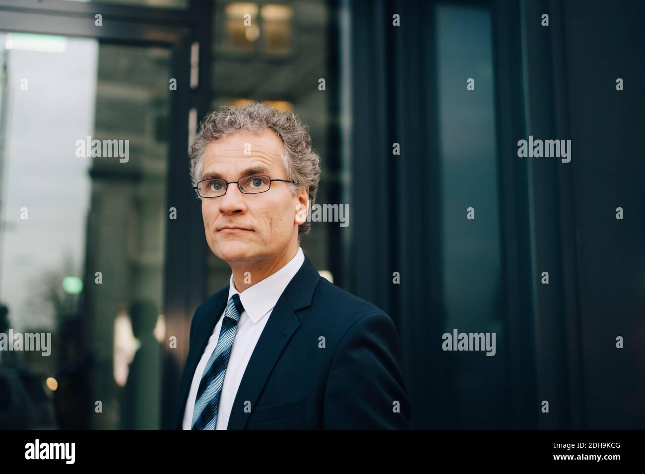 Männlicher Geschäftsmann im Anzug, der in der Stadt steht und wegschaut Stockfoto