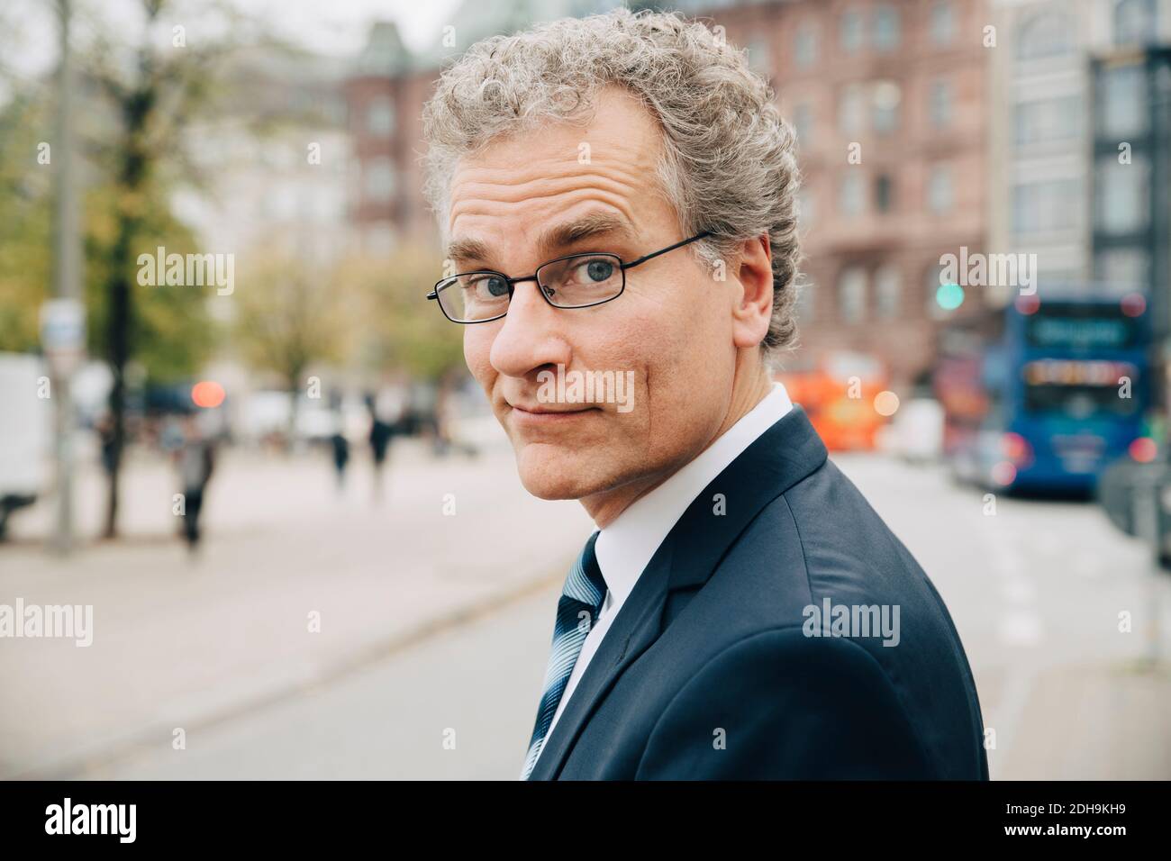 Porträt eines lächelnden Geschäftsmannes in Anzug, während er in der Stadt steht Stockfoto