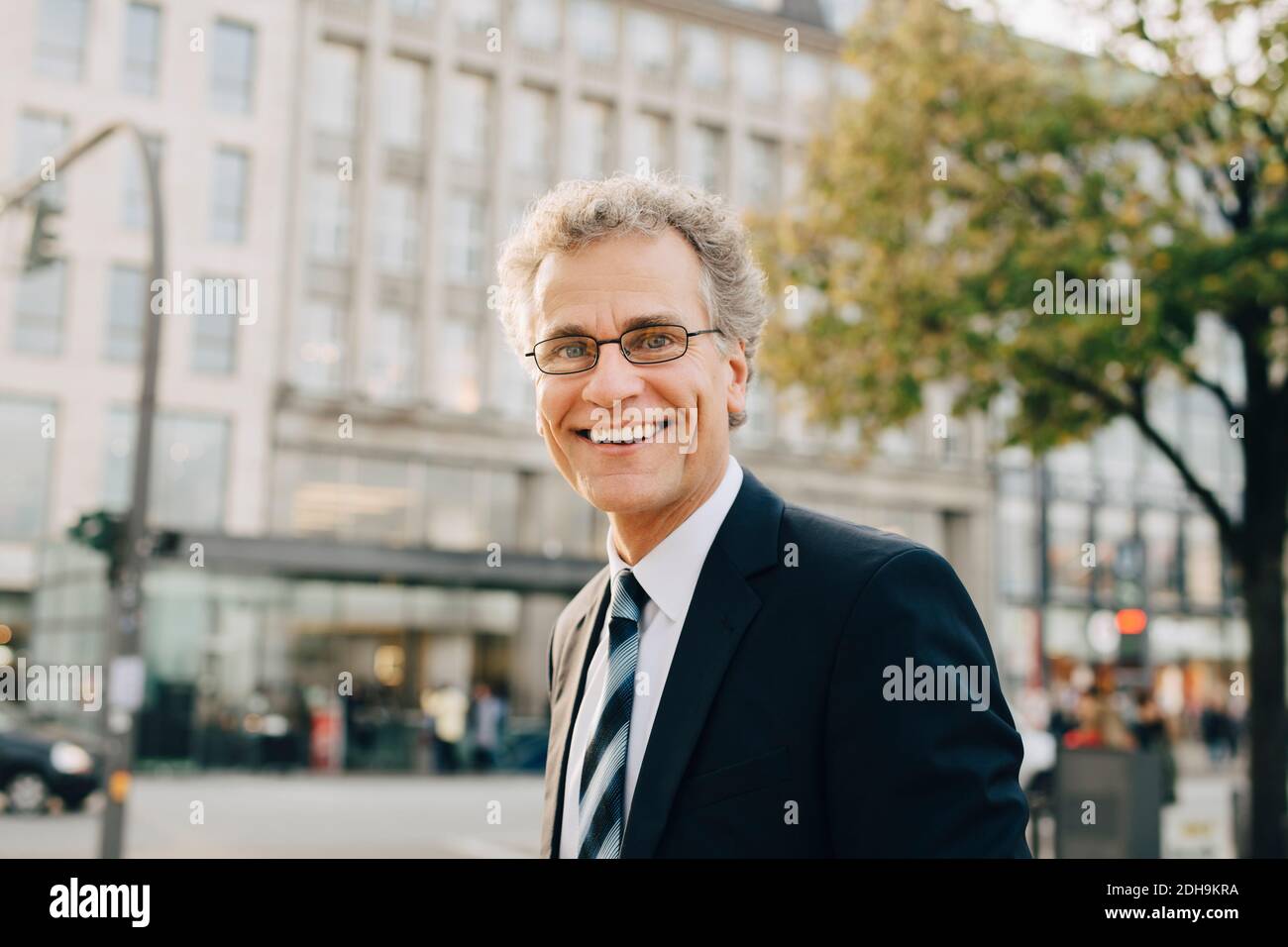 Porträt eines lächelnden Geschäftsmannes in Anzug, während er in der Stadt steht Stockfoto