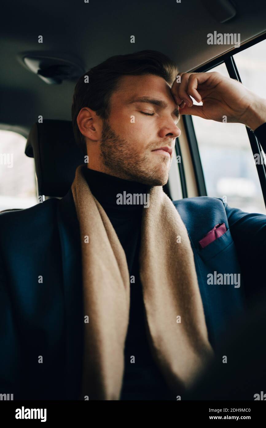 Trauriger Geschäftsmann in Anzug mit geschlossenen Augen im Taxi sitzen Stockfoto