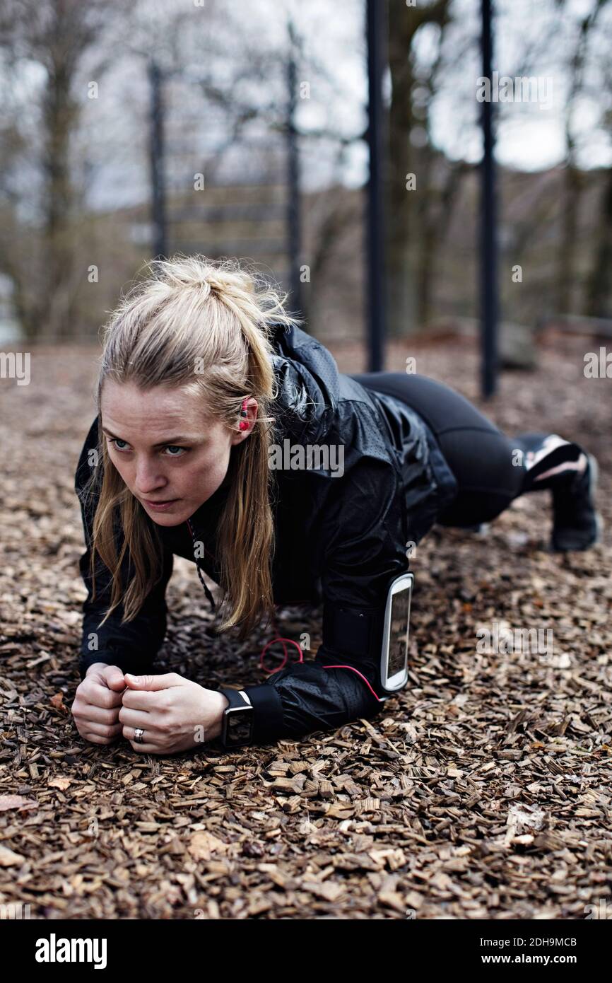 Entschlossene Sportlerin, die Plank-Position im Wald ausführt Stockfoto