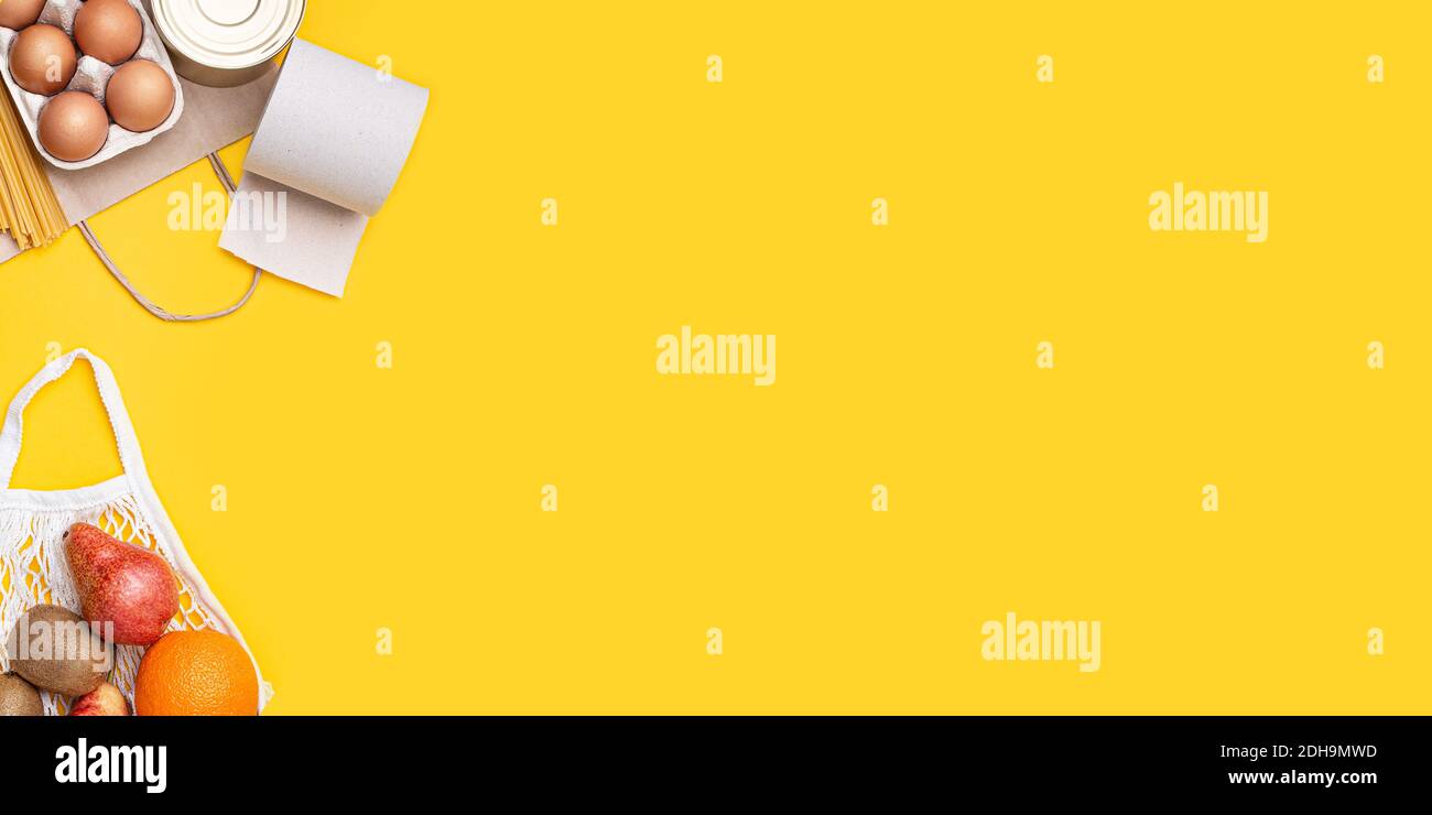 Papiertüte mit Lebensmitteln, Konserven, Tomaten, Gurken, Bananen auf gelbem Hintergrund. Spende, Quarantäne des Coronavirus. Lebensmittel für Quarantäne. Stockfoto