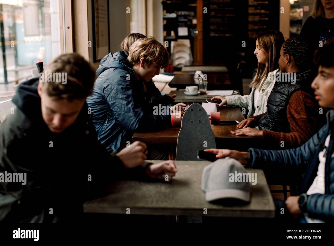 Multiethnische Teenager-Freunde sitzen am Tisch im Café Stockfoto