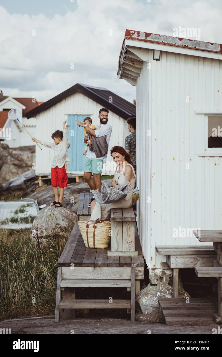 Lächelnder Vater mit Baby-Mädchen zeigt auf Sohn, während Mutter Sitzen in der Hütte Stockfoto