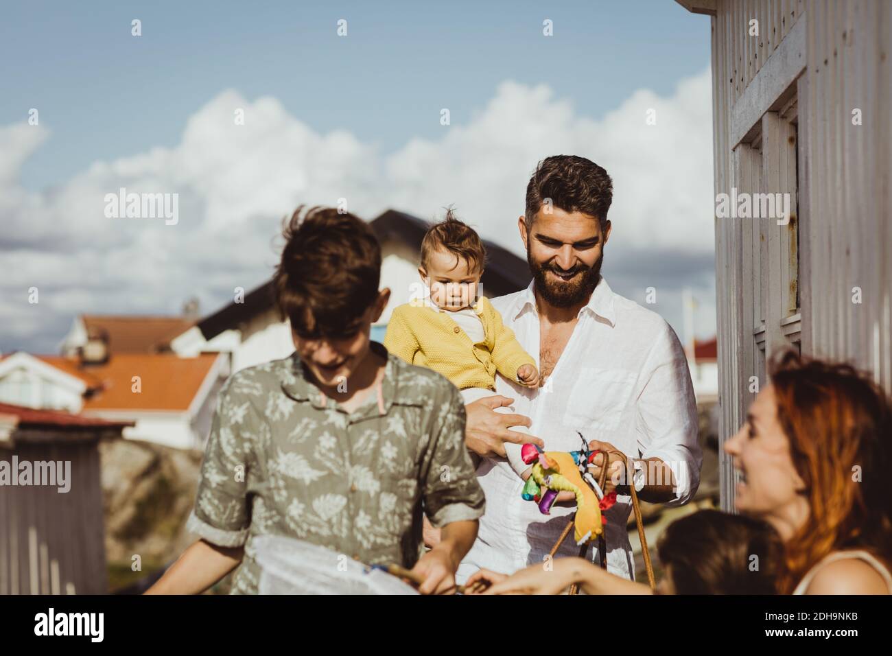 Glücklicher Vater, der seine Tochter trägt, während die Familie lächelt Stockfoto