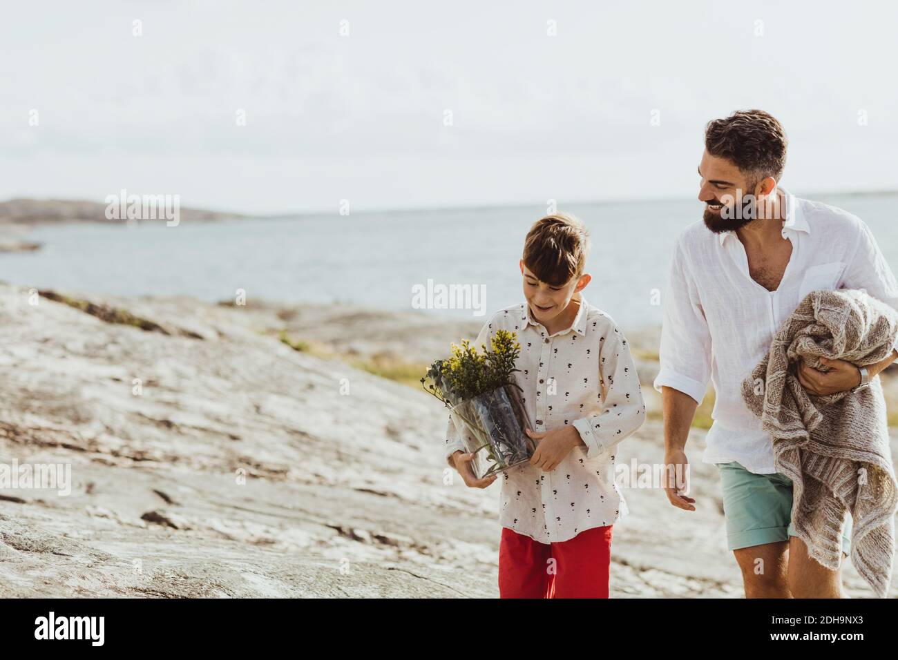 Lächelnder Vater hält Decke während der Verbindung mit Sohn im Sommer Urlaub Stockfoto