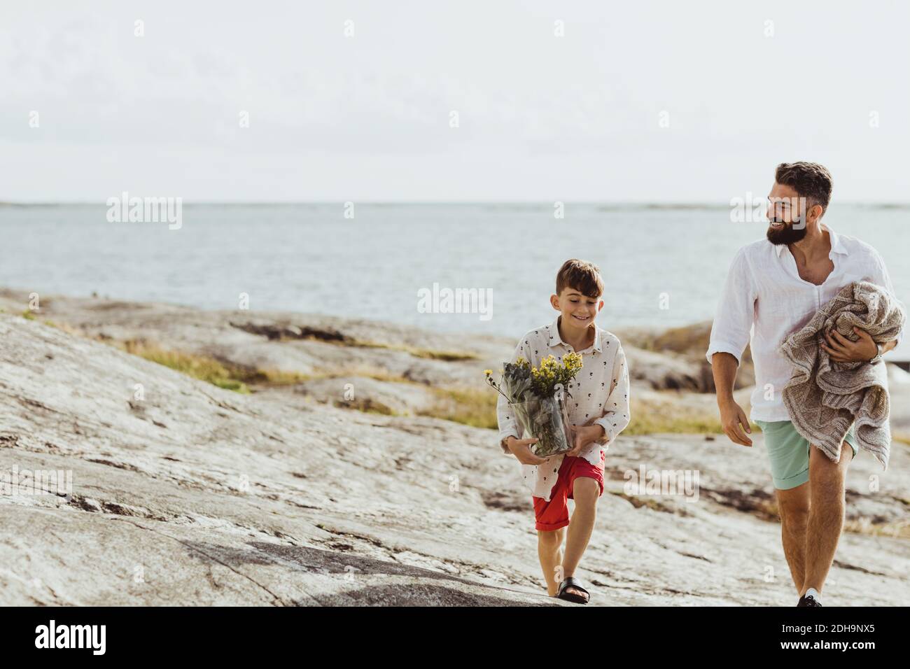 Lächelnder Vater hält Decke während der Verbindung mit Sohn im Sommer Stockfoto