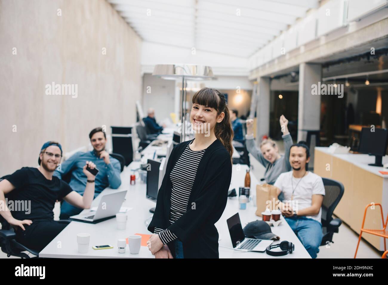 Portrait von glücklichen weiblichen Computer-Programmierer mit Kollegen sitzen an Schreibtisch im Hintergrund Stockfoto