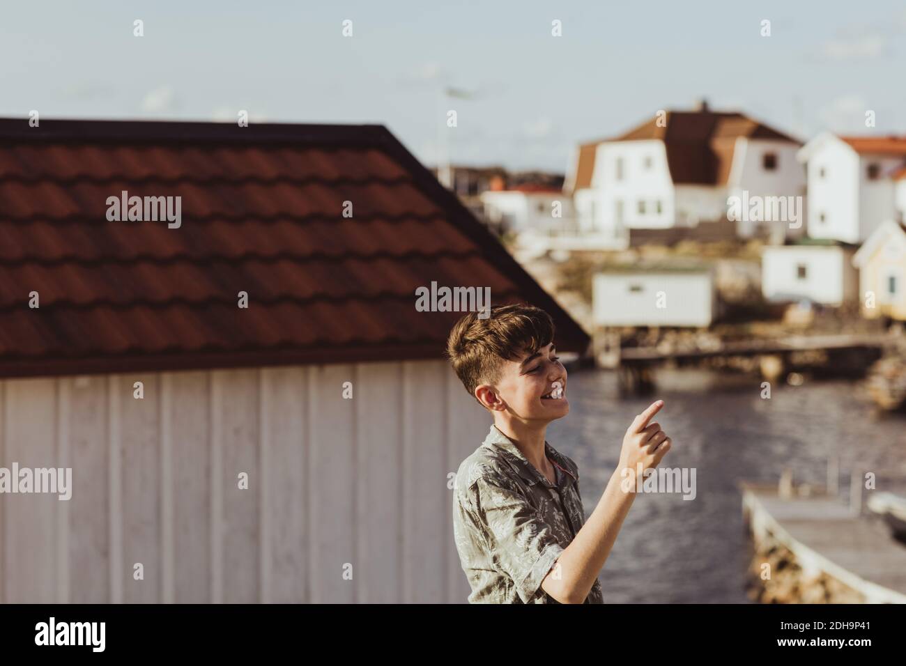 Lächelnder Teenager-Junge zeigt, während er gegen die Hütte steht Stockfoto