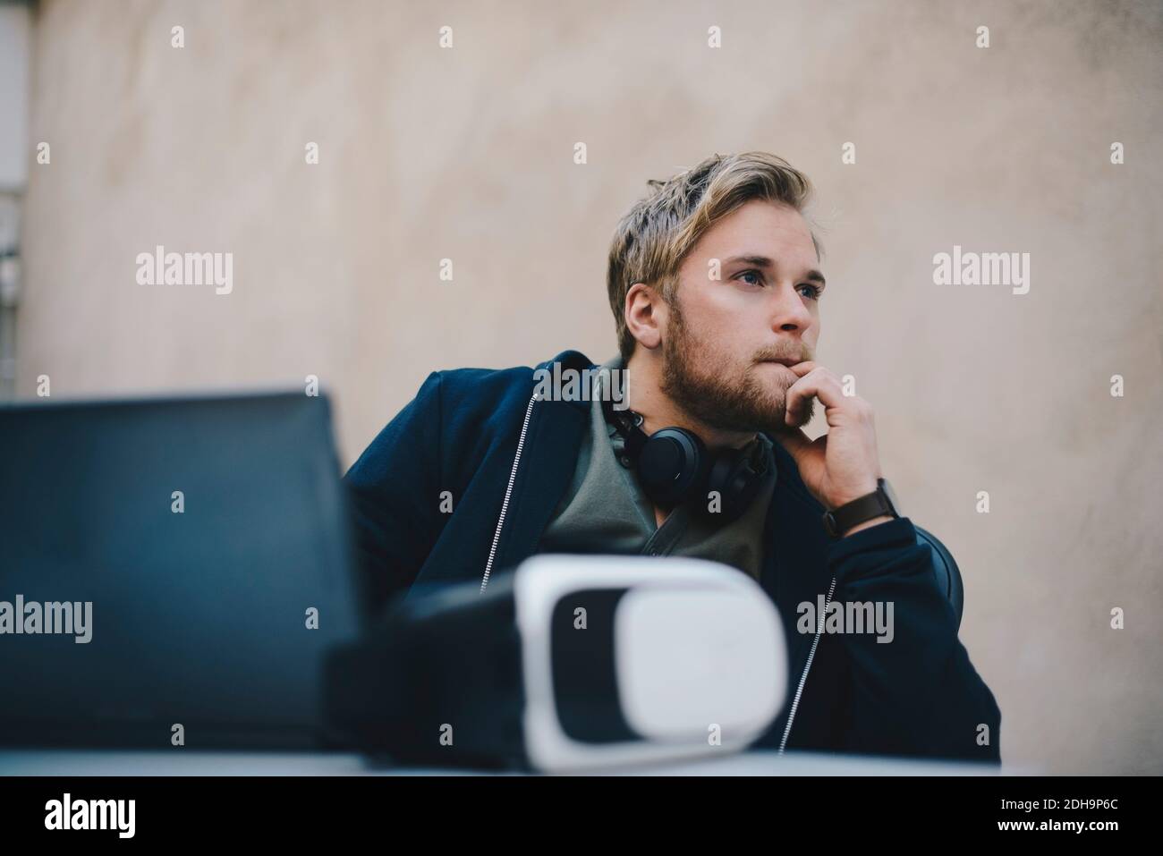 Durchdachter Computerprogrammierer, der wegschaut, während er am Schreibtisch sitzt Büro Stockfoto