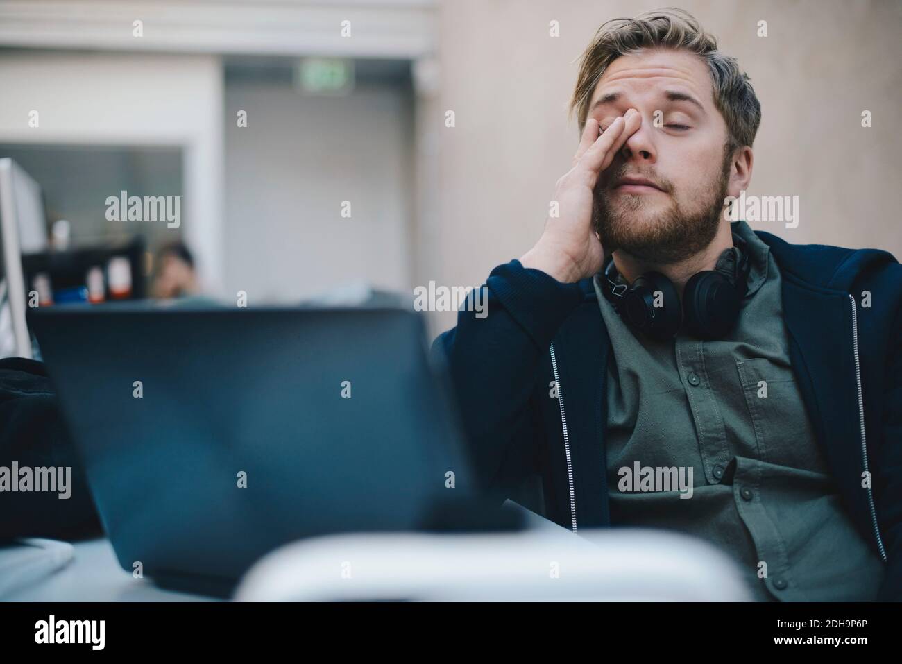 Müde Computer Programmierer reiben Augen während im Büro sitzen Stockfoto