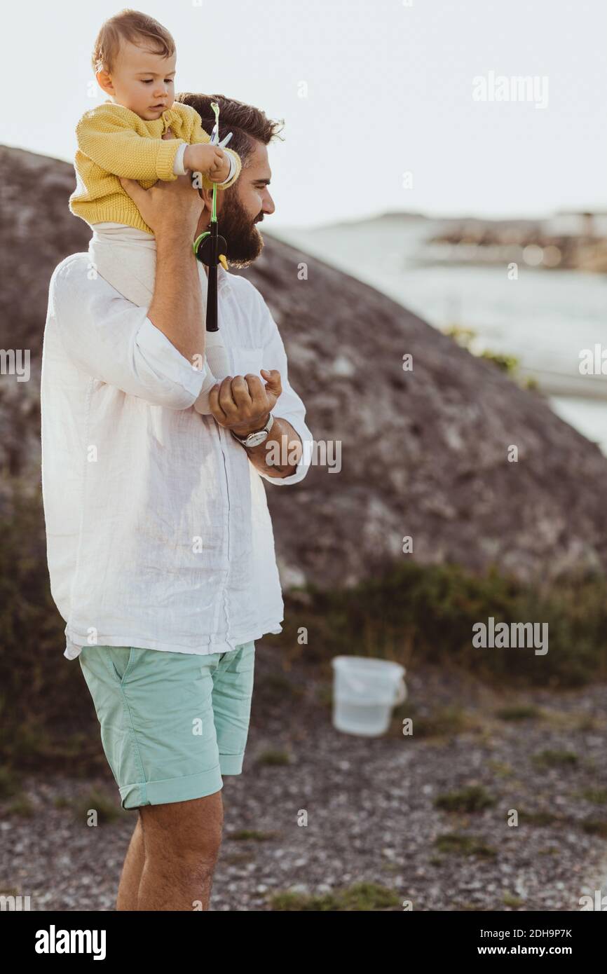 Vater trägt Tochter auf der Schulter, während er auf Felsformation steht Stockfoto