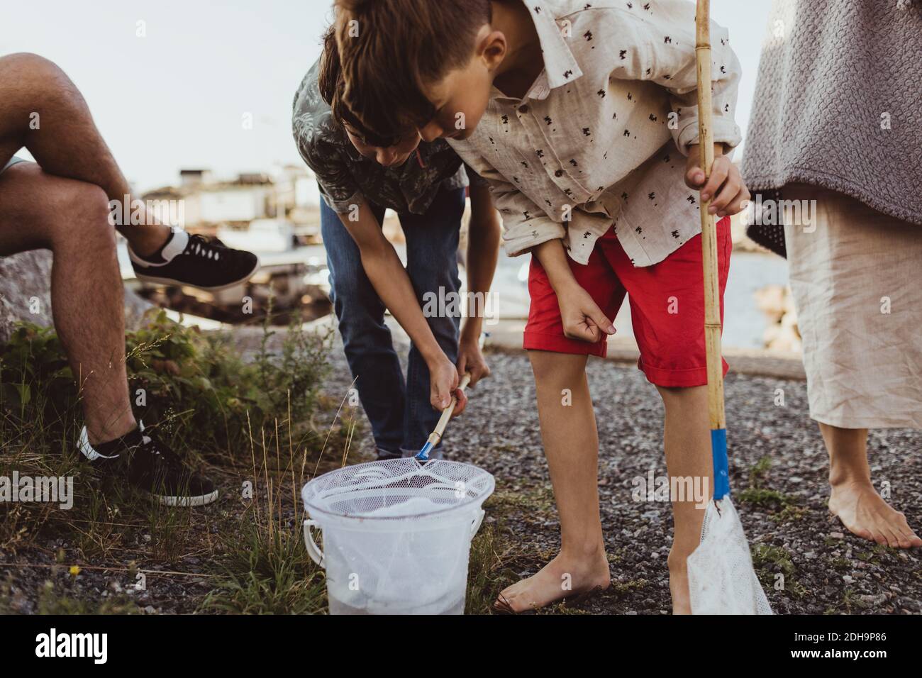 Bruder, der Eimer durch Fischernetz beim Biegen durch schaut Geschwister über dem Archipel Stockfoto