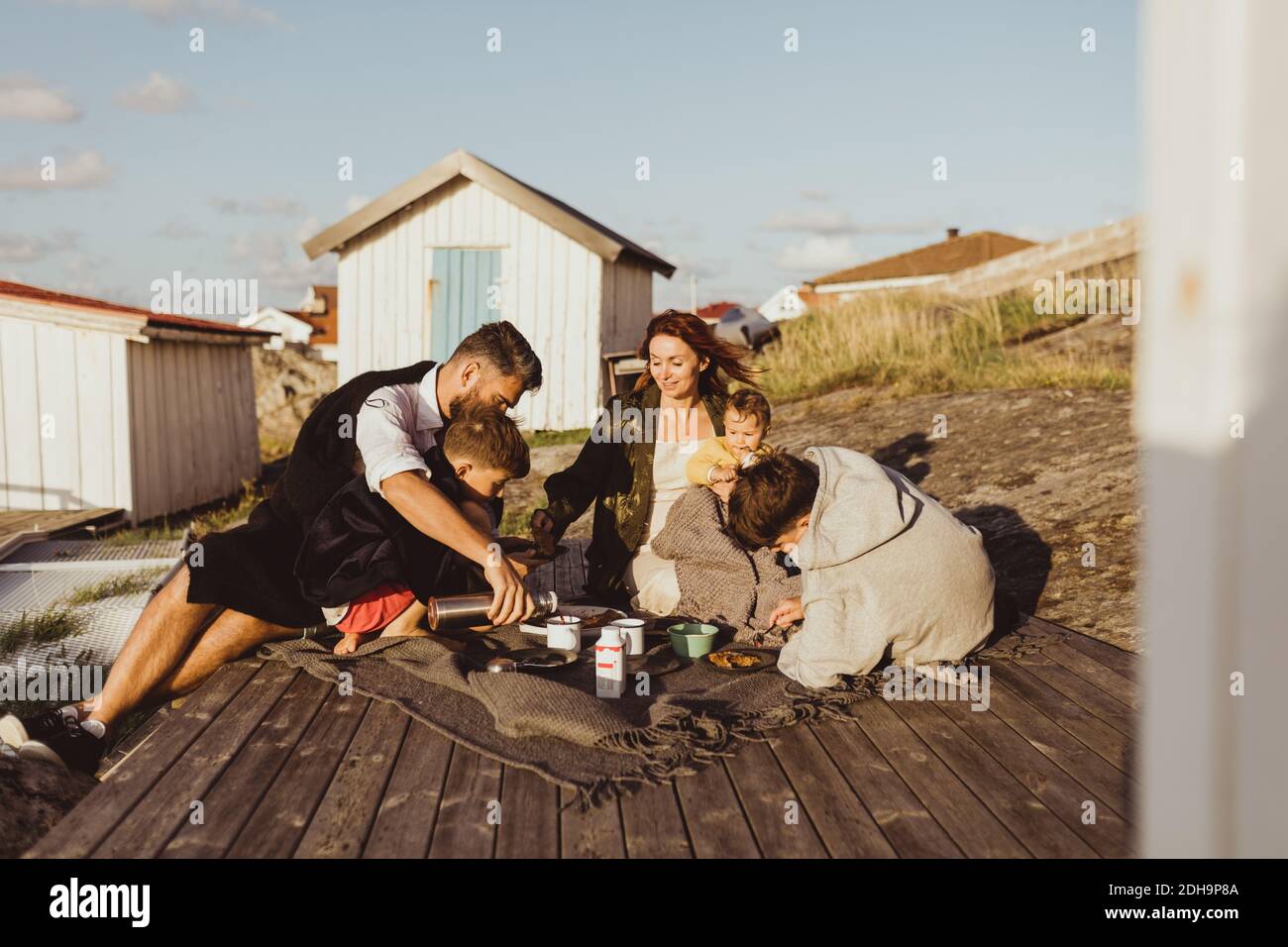 Familie mit Kindern, die im Sommer draußen auf der Decke sitzen Stockfoto