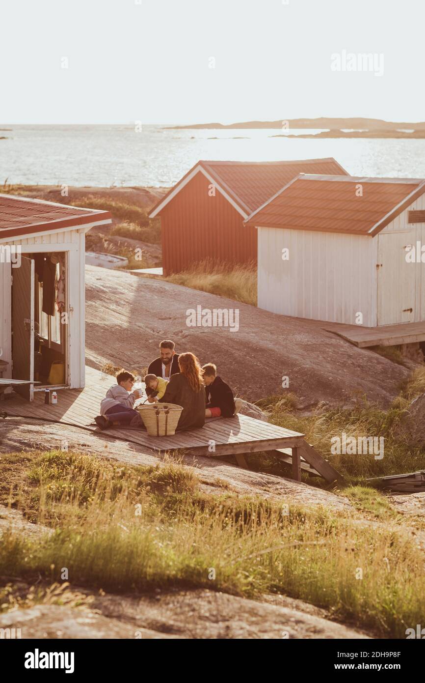 Blick auf die Familie mit Kindern, die draußen in der Hütte sitzen An sonnigen Tagen Stockfoto