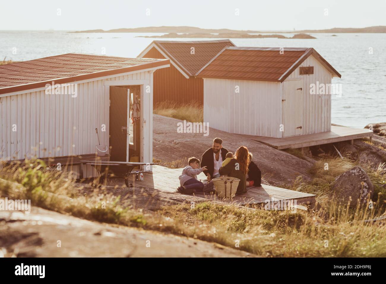 Blick auf die Familie mit Kindern, die draußen in der Hütte sitzen Im Sommer Stockfoto