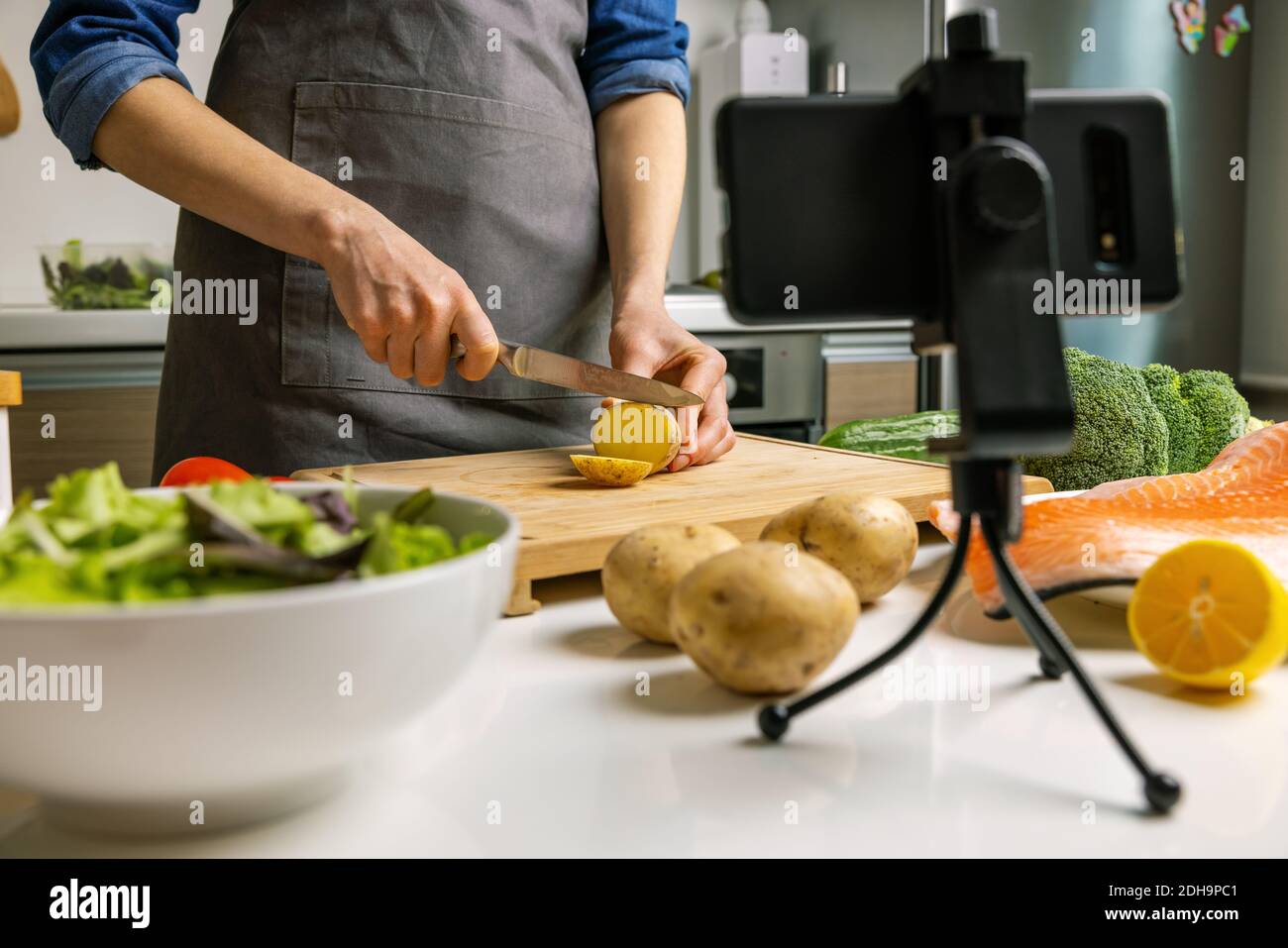 Food Blogger Aufnahme Video mit Handy-Kamera in der Küche zu Hause. Schneiden von Kartoffeln auf Holzbrett Stockfoto