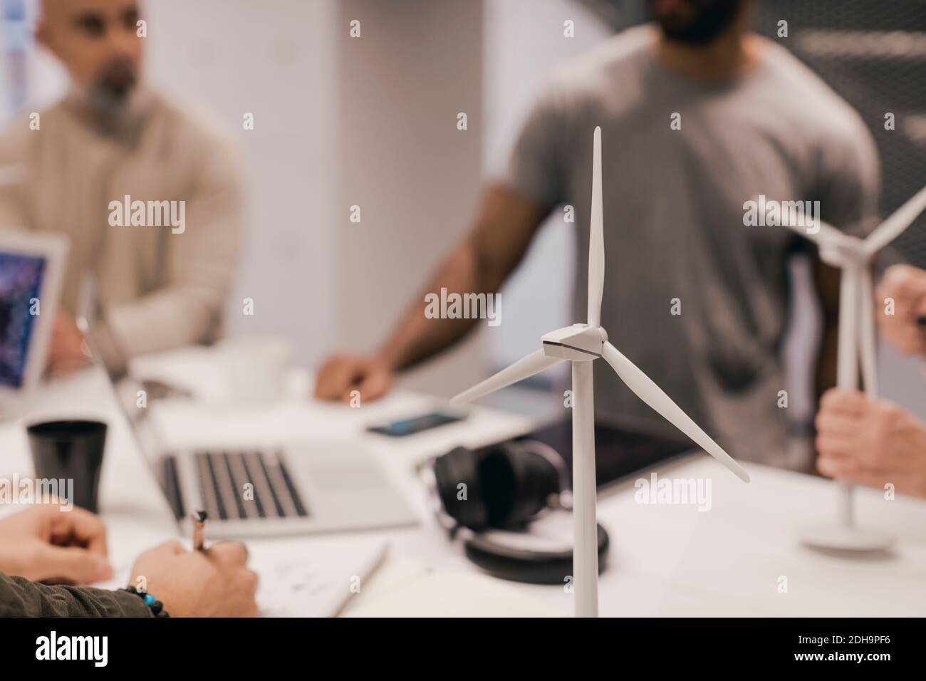 Nahaufnahme von Windmühlenmodellen auf dem Schreibtisch mit Geschäftsleuten Hintergrund Stockfoto