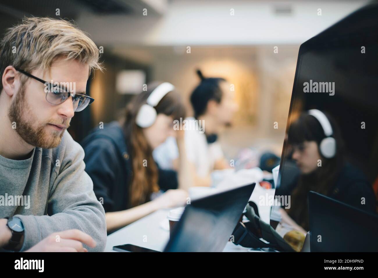 Männlicher Programmierer, der am Computer mit Kollegen am Schreibtisch arbeitet Büro Stockfoto