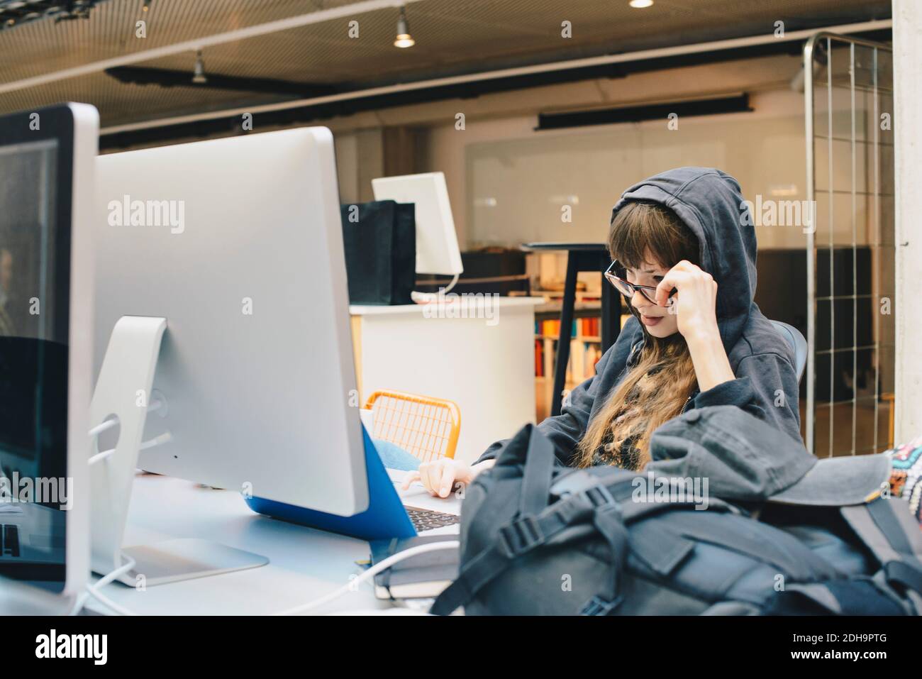 Weibliche Computer-Programmierer mit Laptop beim Blick über Brillen in Büro Stockfoto