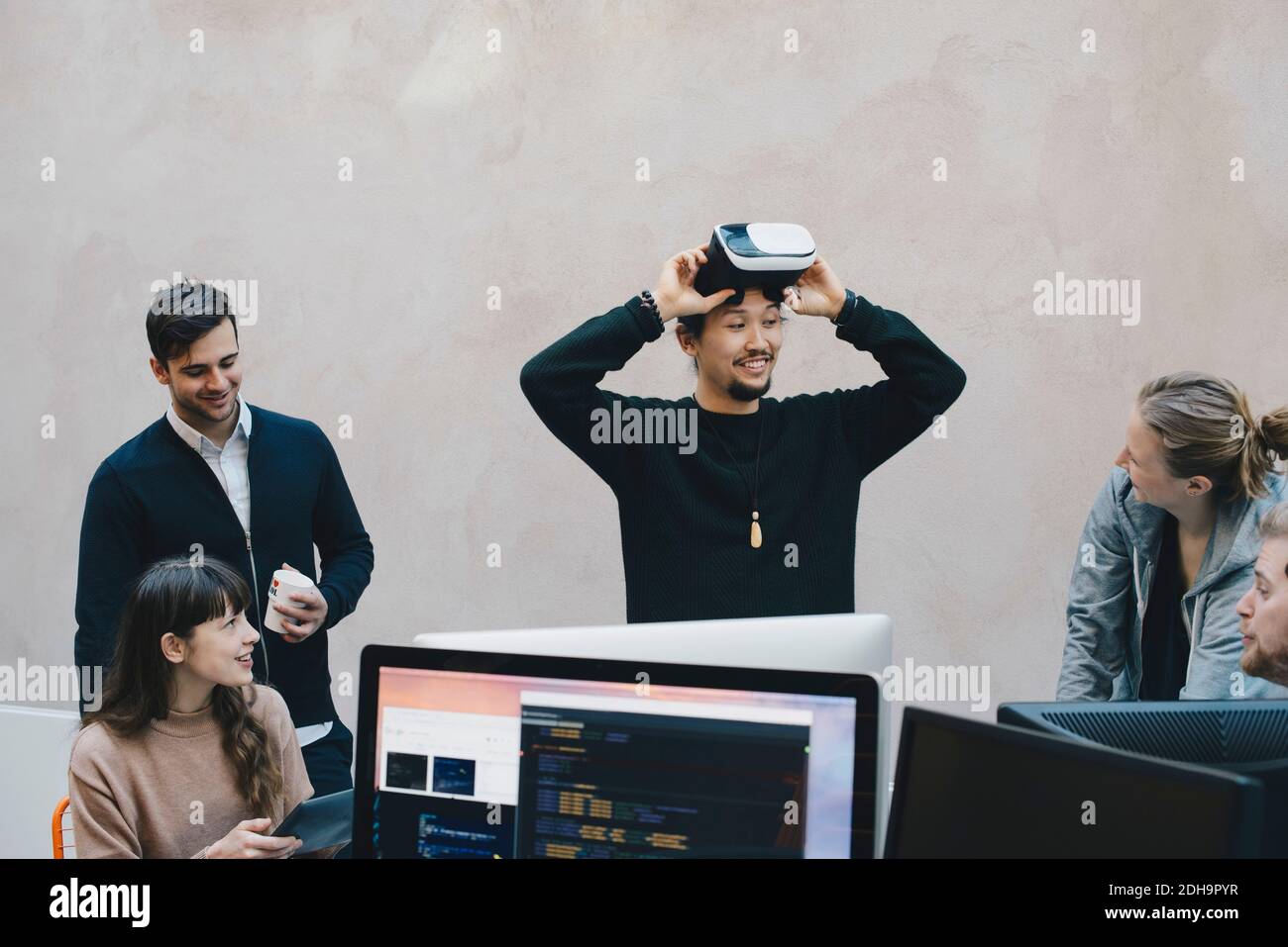 Männlicher Computerprogrammierer, der VR-Brille trägt, während er Kollegen anschaut Im Büro Stockfoto