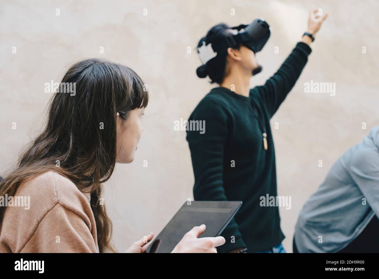 Männlicher Computerprogrammierer, der während der Verwendung von VR-Brillen von Kollegen gestikuliert Im Büro Stockfoto