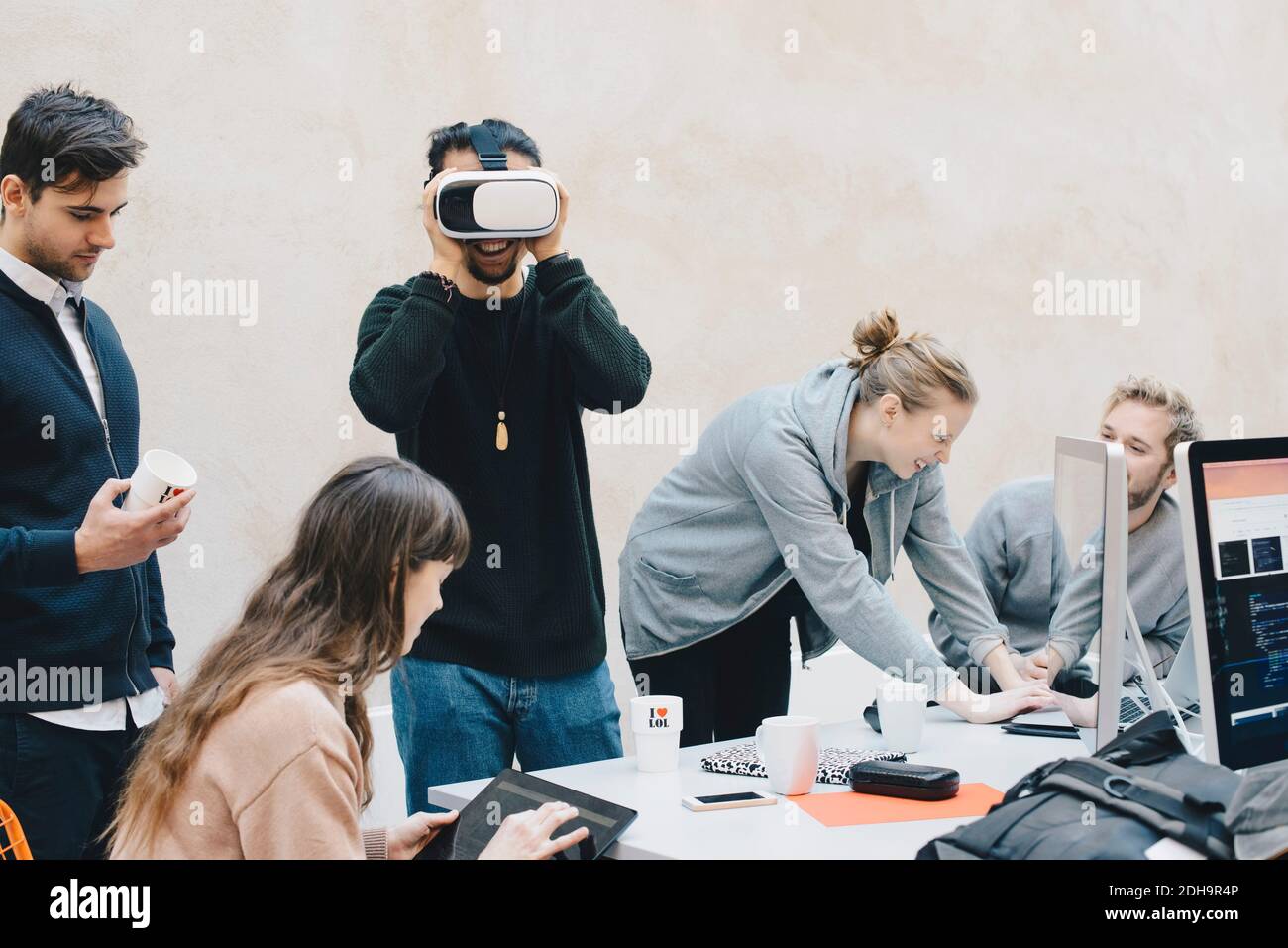 Männlicher Computerprogrammierer mit VR-Brille, während Kollegen arbeiten in Büro Stockfoto