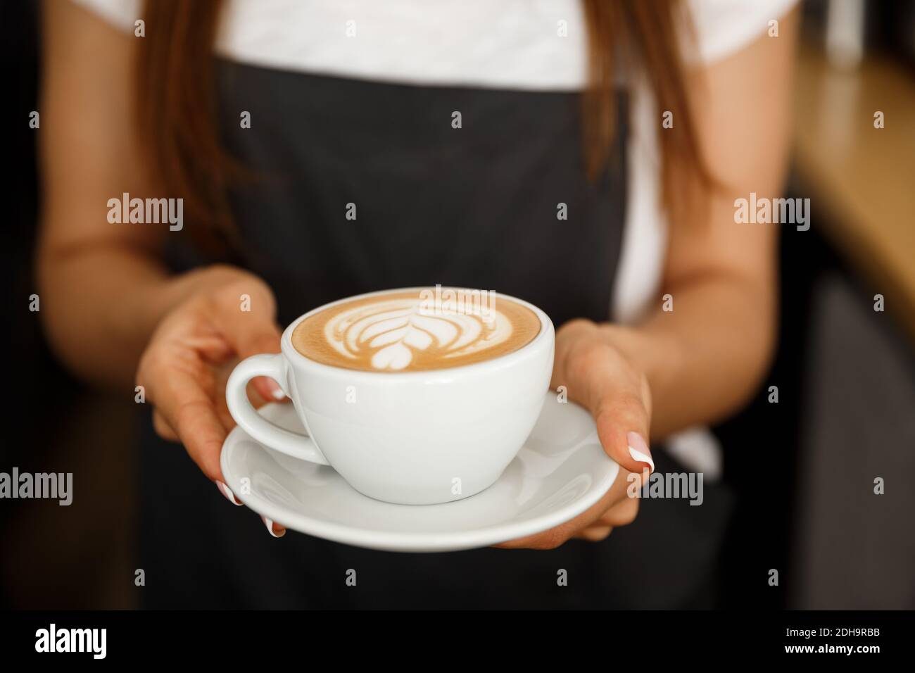 Coffee Business Concept - Nahaufnahme von weiblichen Kaffeespezialitäten mit Latte Art im Coffeeshop. Fokus auf Femal Stockfoto