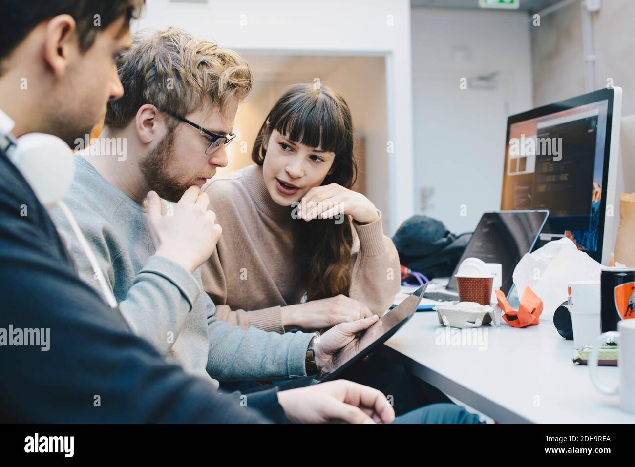 Männliche und weibliche Computer-Programmierer diskutieren über digitale Tablette an Schreibtisch im Büro Stockfoto