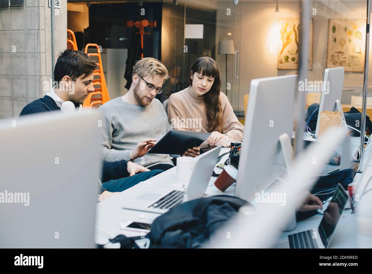 Männliche und weibliche Computerprogrammierer, die digitale Tablette am Schreibtisch benutzen Im Büro Stockfoto
