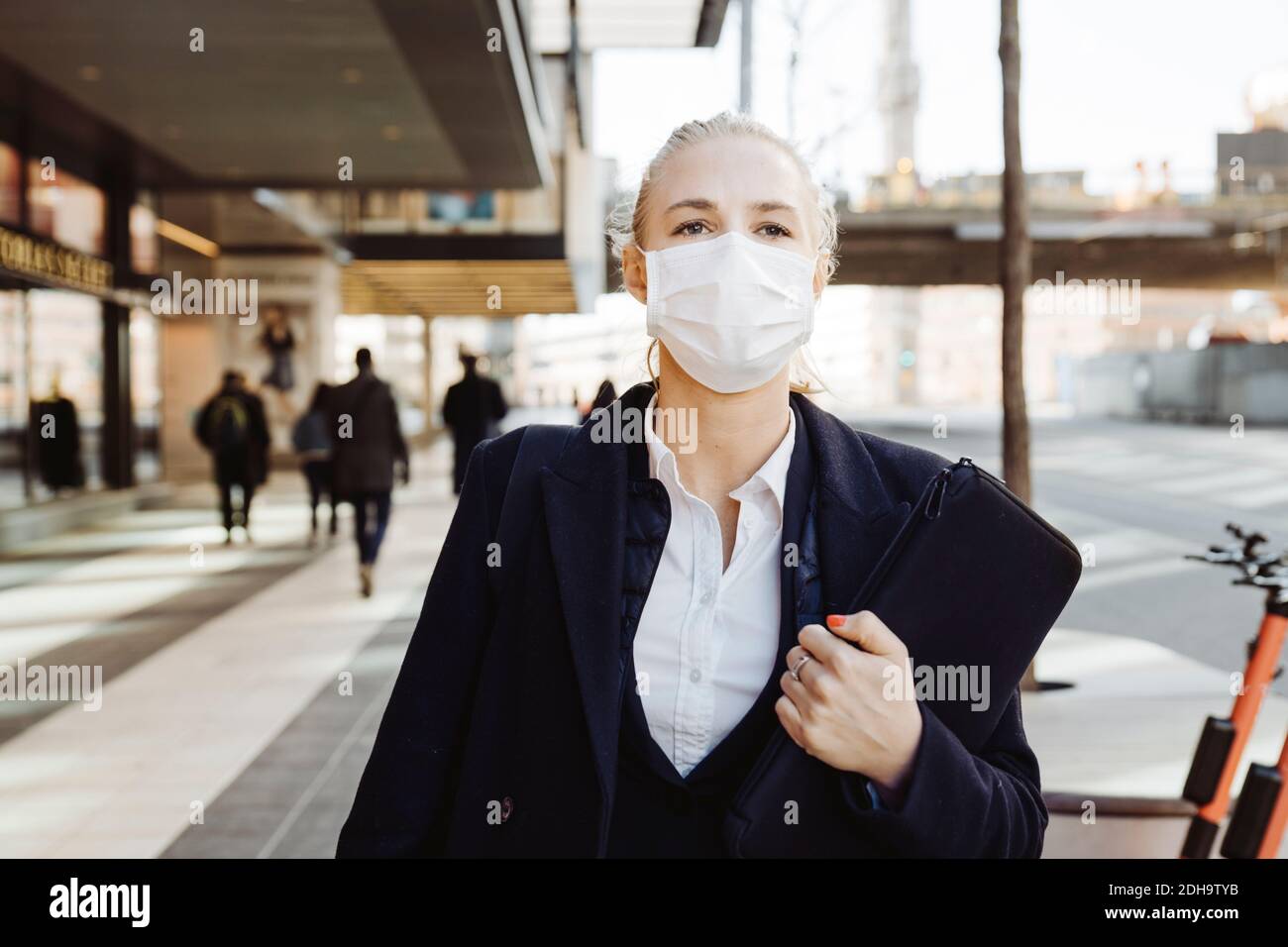 Geschäftsfrau, die in der Straße mit Gesichtsmaske geht Stockfoto