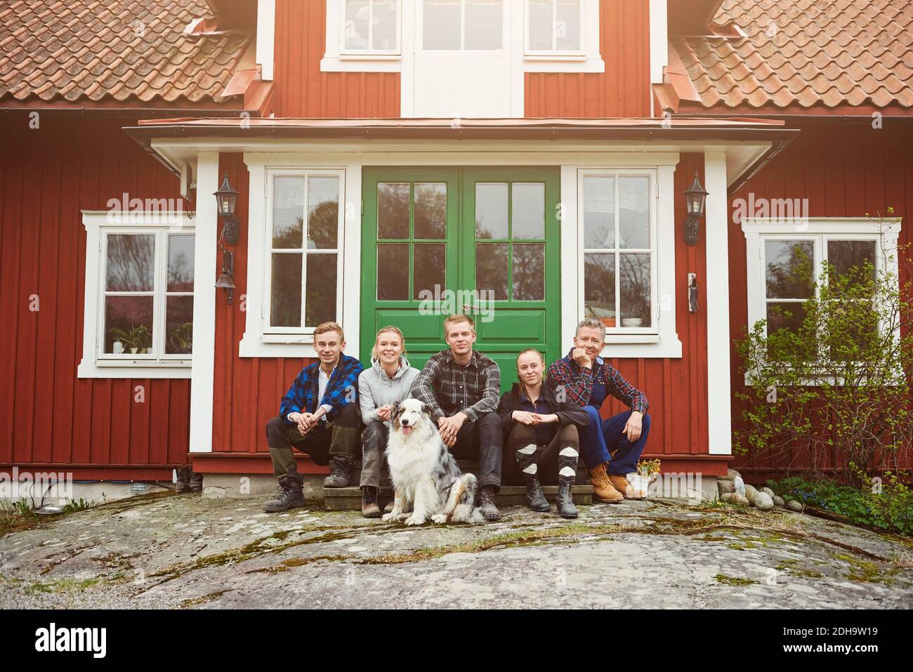 Porträt der Familie sitzt mit Australian Shepherd am Eingang von Haus Stockfoto