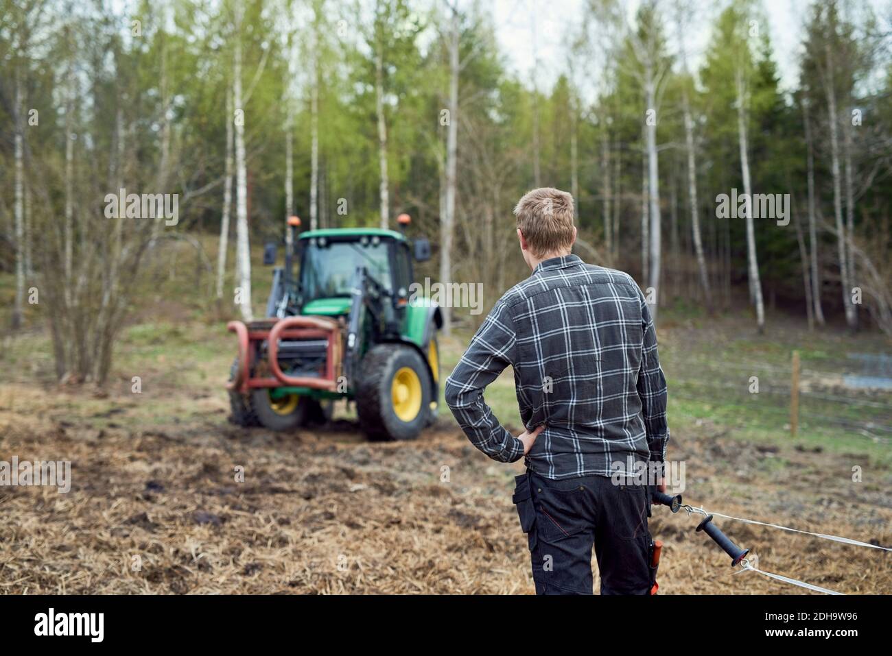 Rückansicht des Landwirts, der Stahlseil hält, während er darauf steht Ein Stockfoto