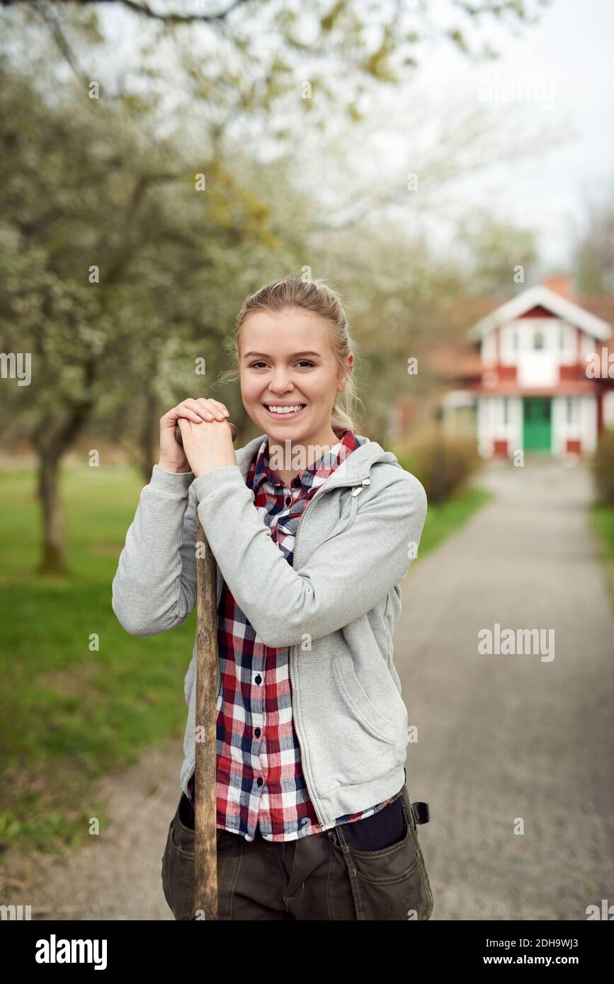 Portrait von lächelndem Teenager-Mädchen, das Pitchfork hält, während es auf steht Fußweg Stockfoto